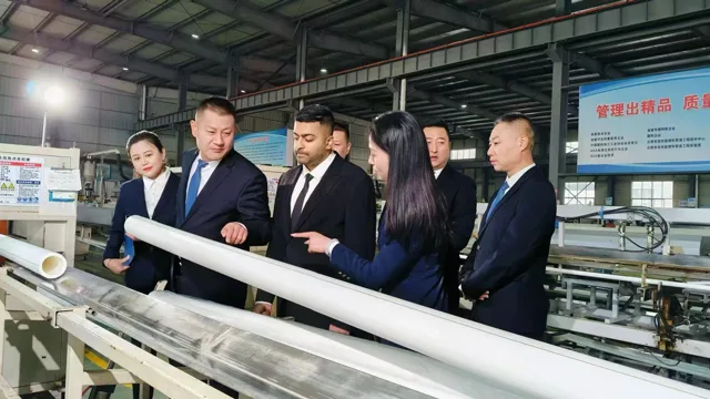 Aamir Malik examining a length of pipe beside a production line.